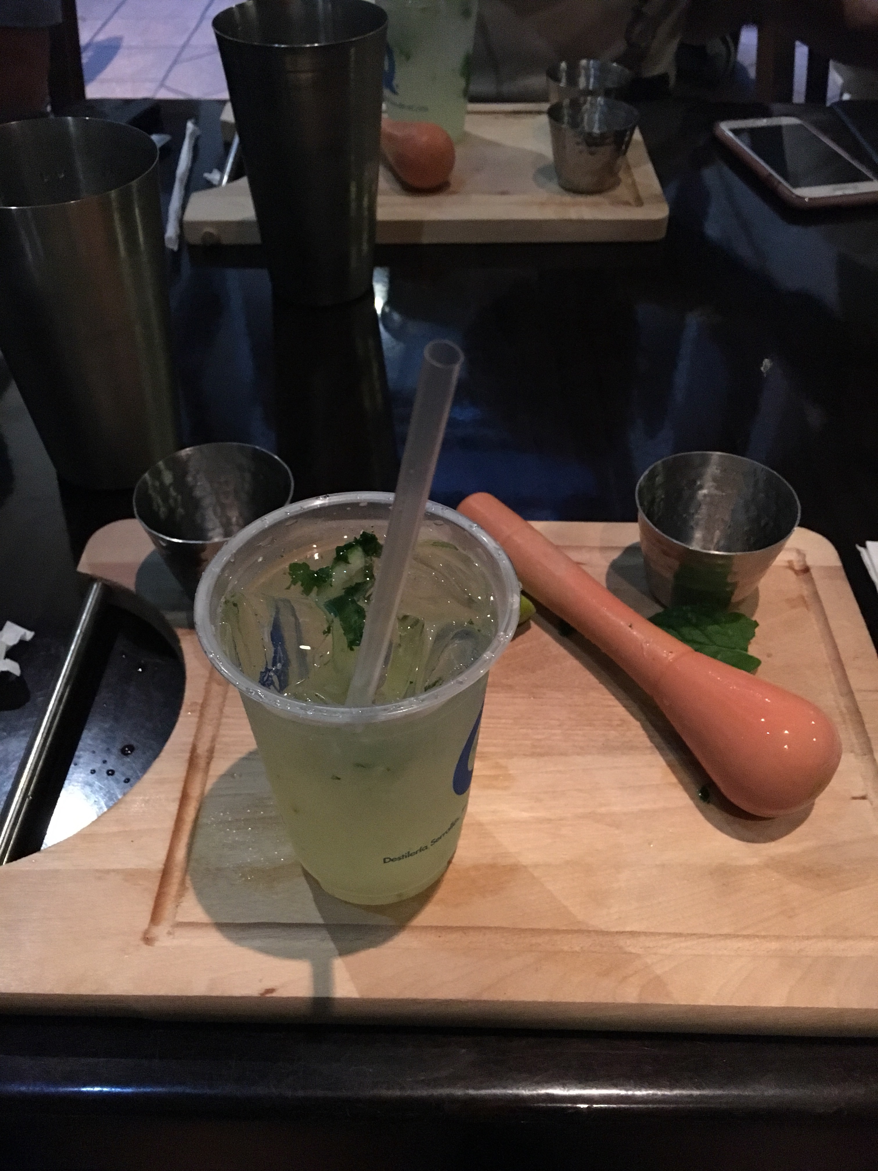 A green alcoholic drink, freshly made on a chopping board with pestle beside in it, in post titled #SoSS sharing
