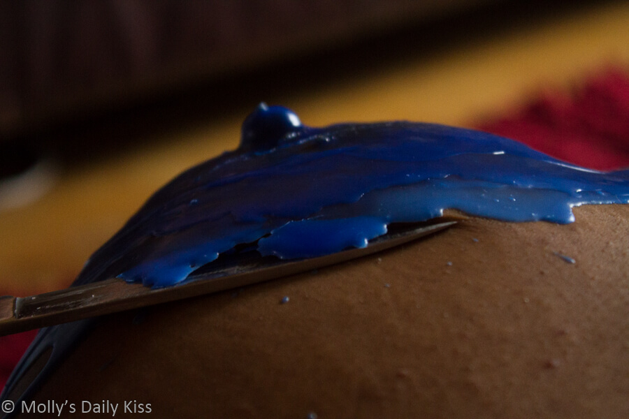 Cara's breast covered in blue wax with a knife against it