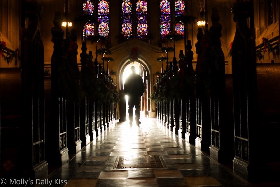 A church aisle with a man in silhouette standing in the sunshine